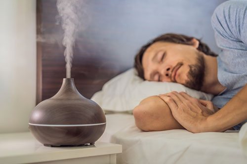 Man-in-deep-sleep-wtih-oil-diffuser-next-to-bed